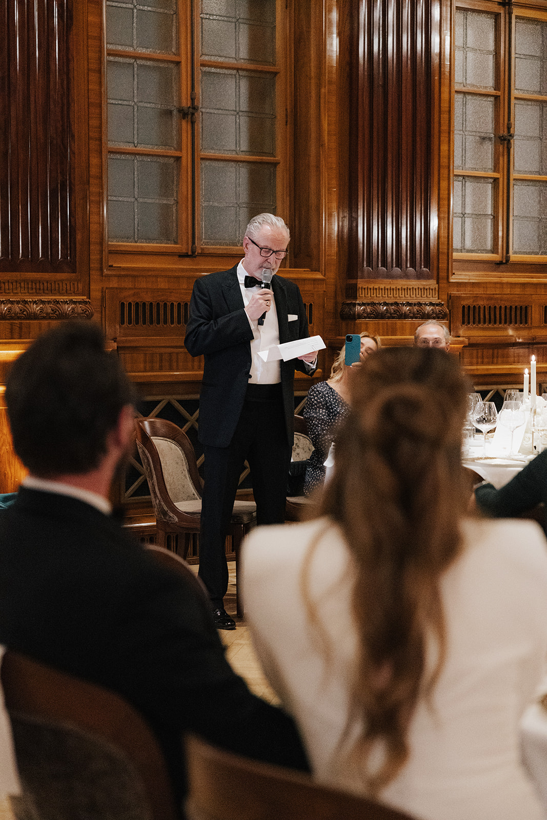 Father of the bride giving an emotional wedding speech during the reception at Park Hyatt Vienna, standing in front of wood-paneled walls.