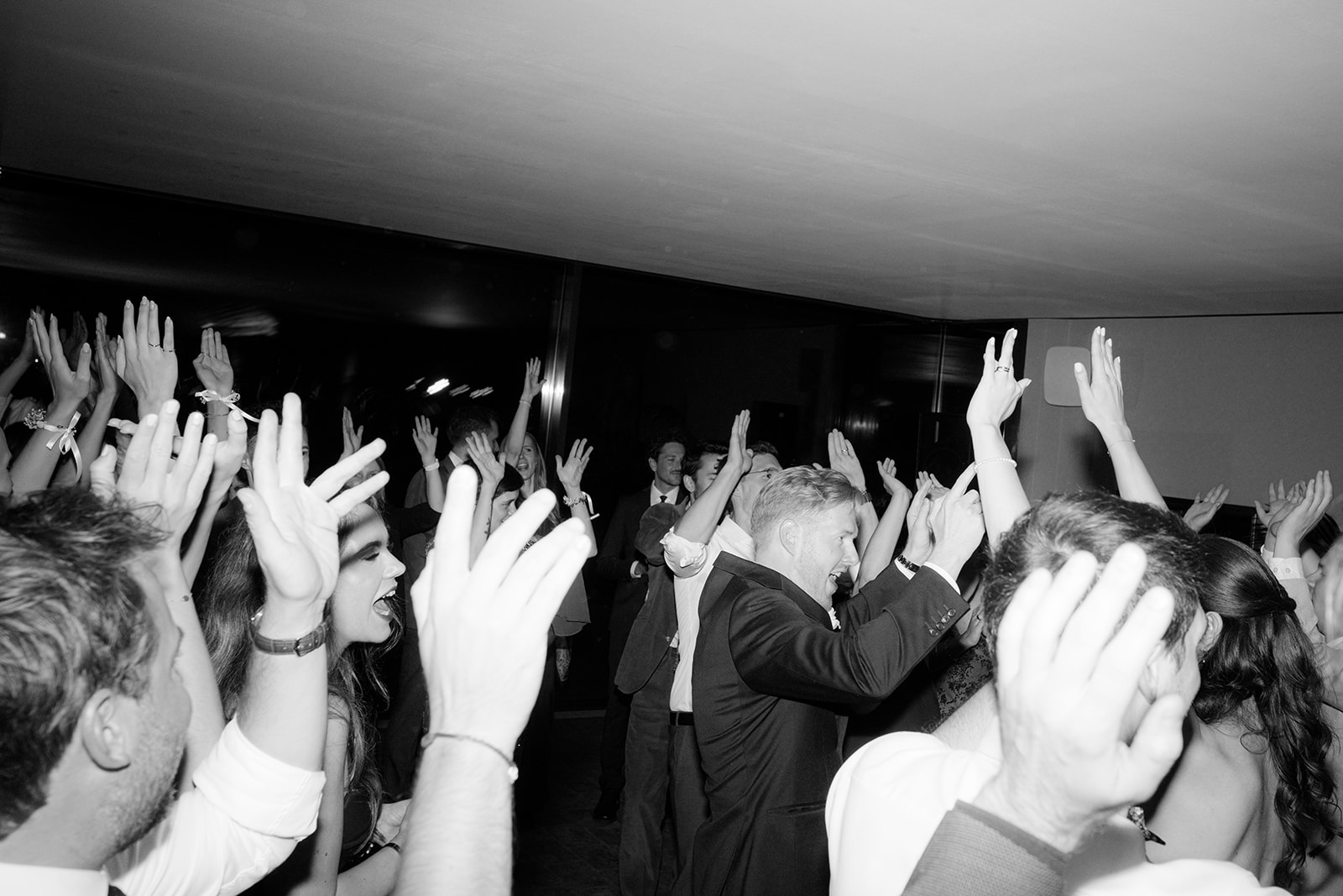 Black and white photo of guests dancing with hands in the air at a wedding party Am Reisenberg in Vienna