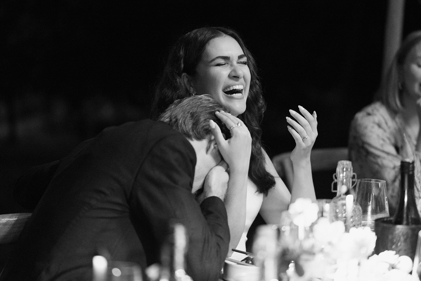 Black and white photo of a bride laughing with the groom during the wedding dinner at Franz von Grün