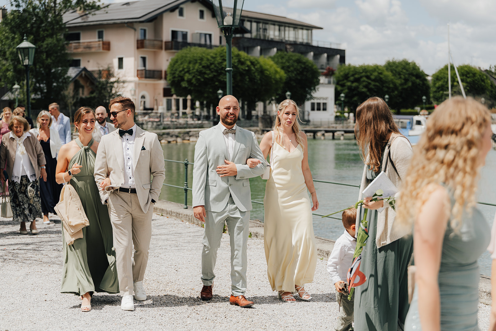 Bride, groom and guests walking along the lake promenade at Mattsee in Salzburg