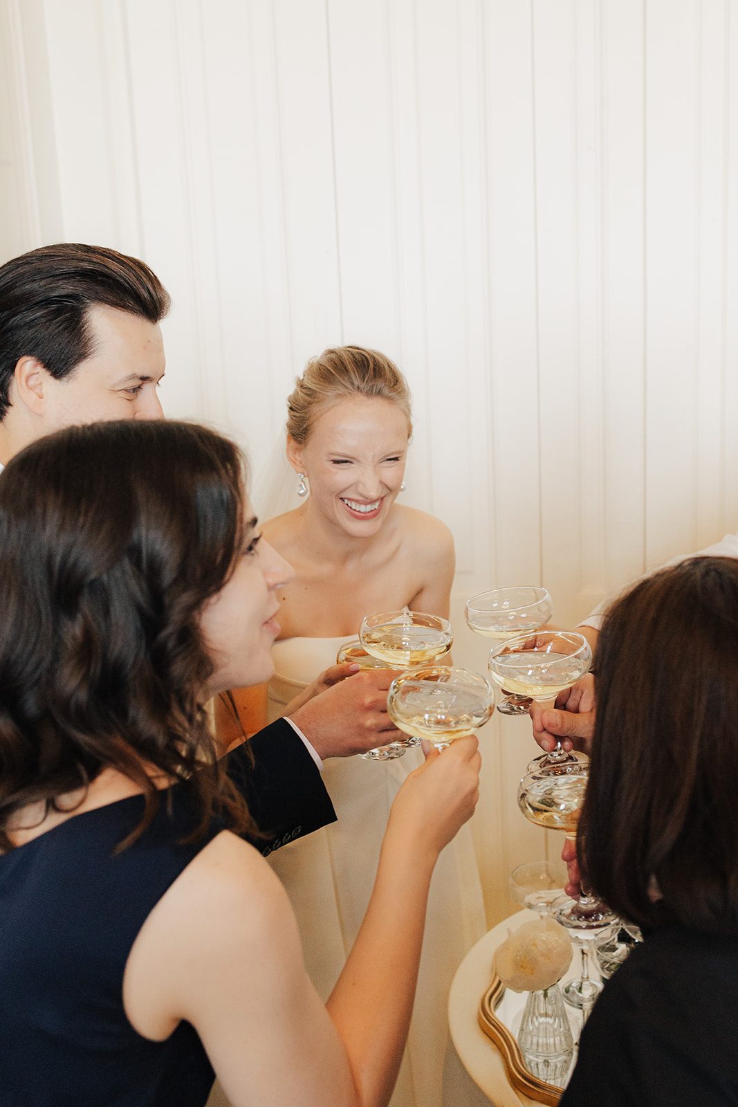 Bride laughing and toasting with champagne among her friends at a Palais Chotek wedding in Vienna