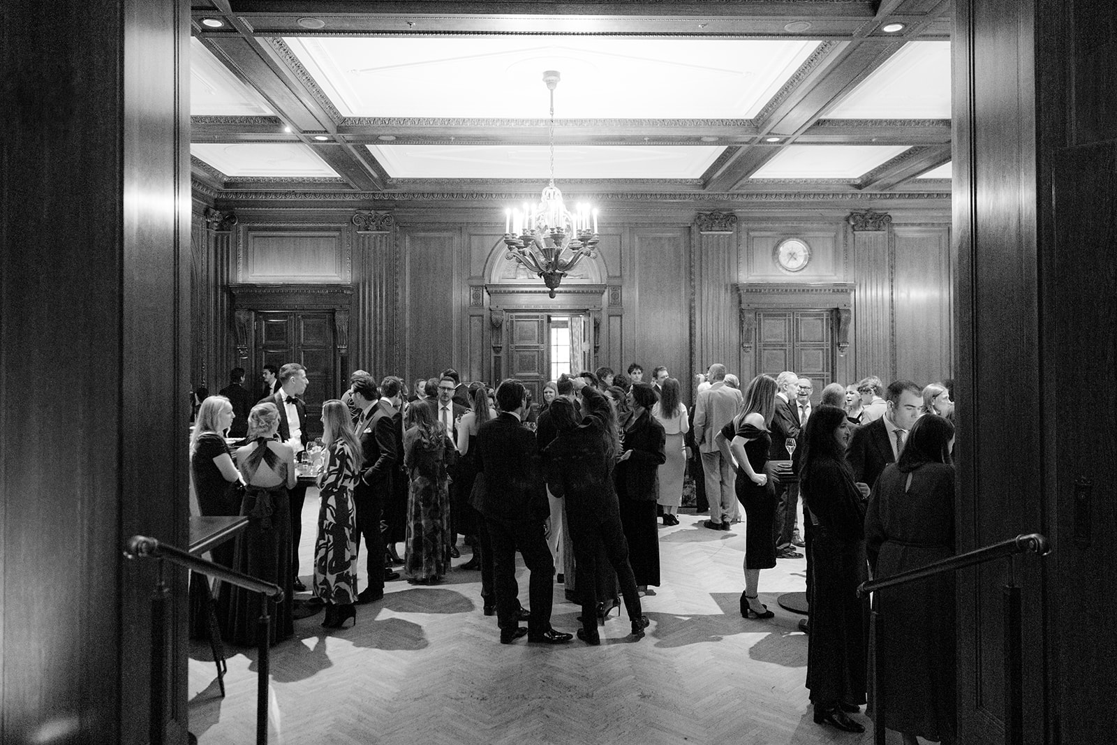 Black and white photo of guests at the wedding reception in the wood-panelled hall of Park Hyatt Vienna