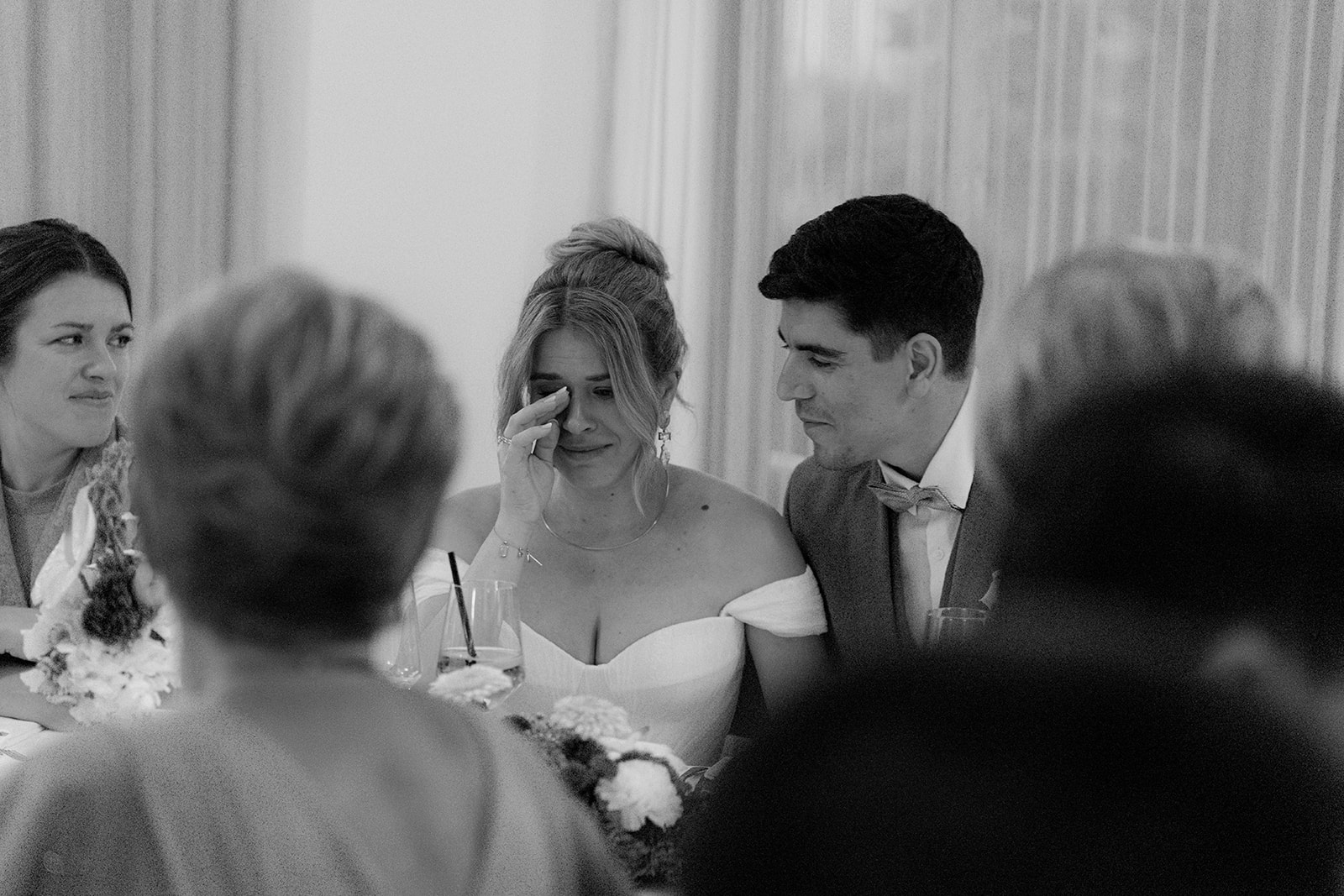 Black and white photo of an emotional bride with her guests at dinner, wedding at Refugium Hochstrass in Lower Austria