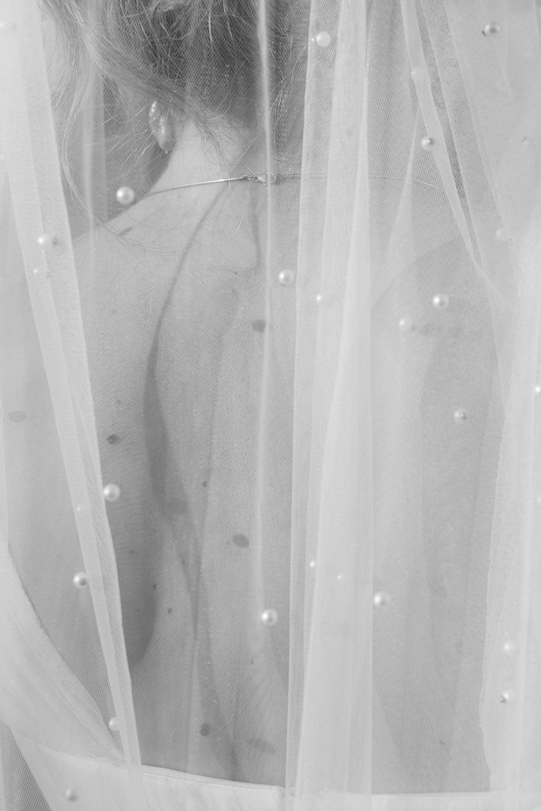 Black and white detail of a pearl veil over the bride's back, wedding at Refugium Hochstrass