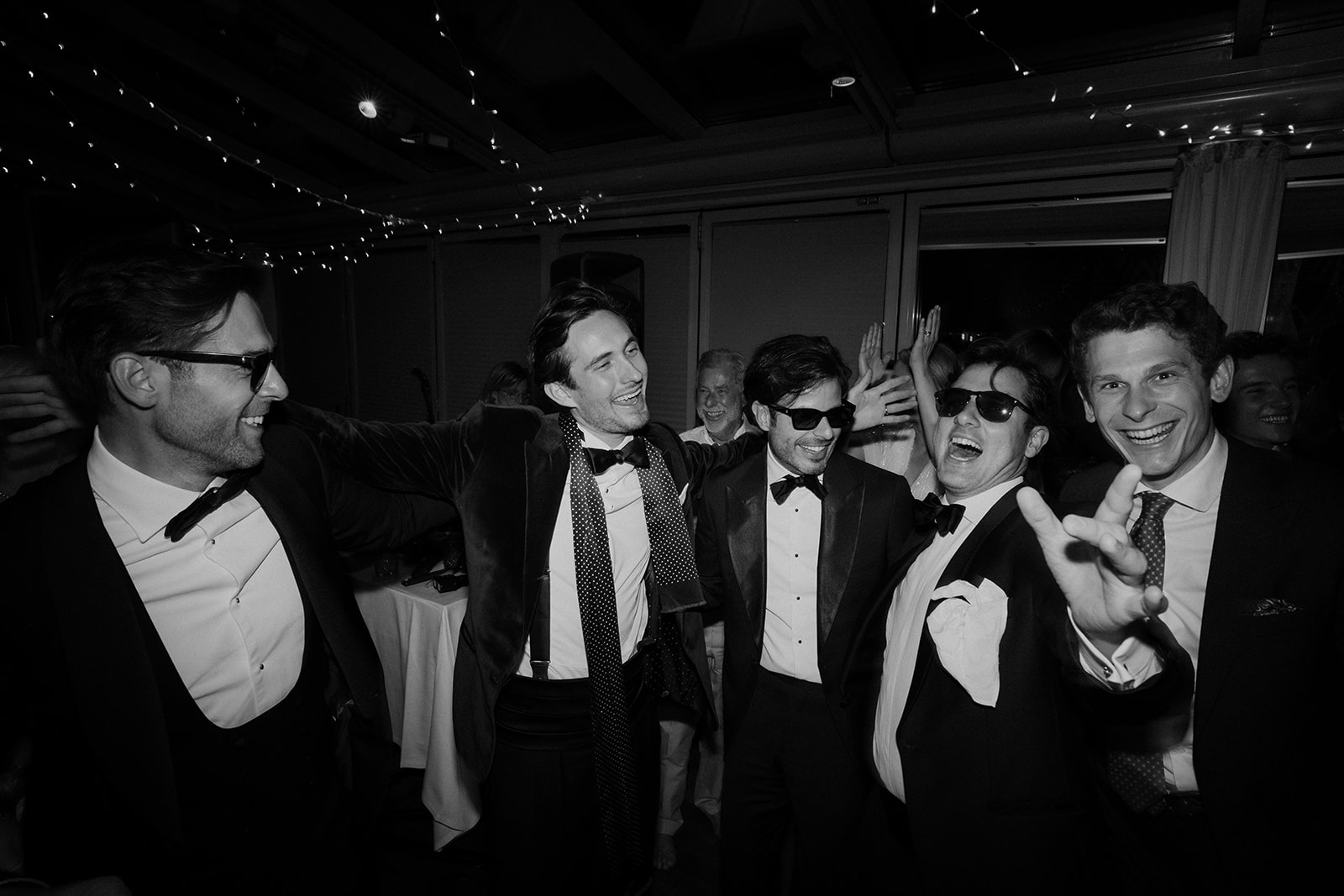 Black and white photo of groomsmen in tuxedos celebrating at a rooftop wedding party in Vienna