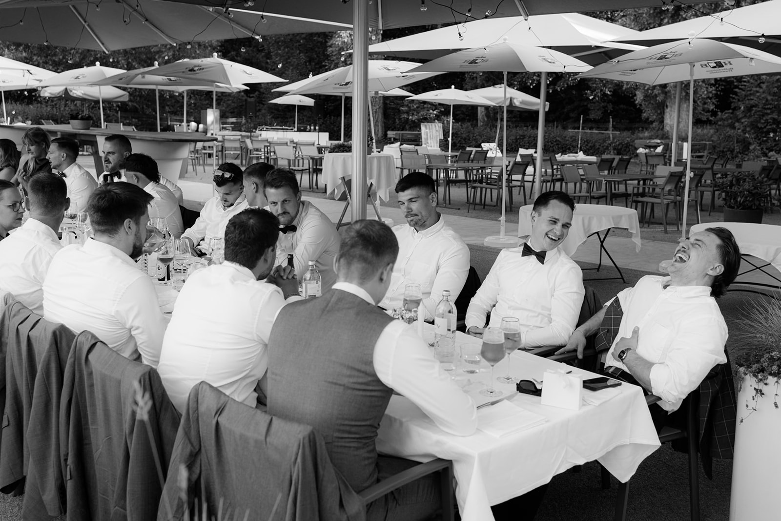 Wedding guests at a long table under parasols at a lakeside dinner in Salzburg