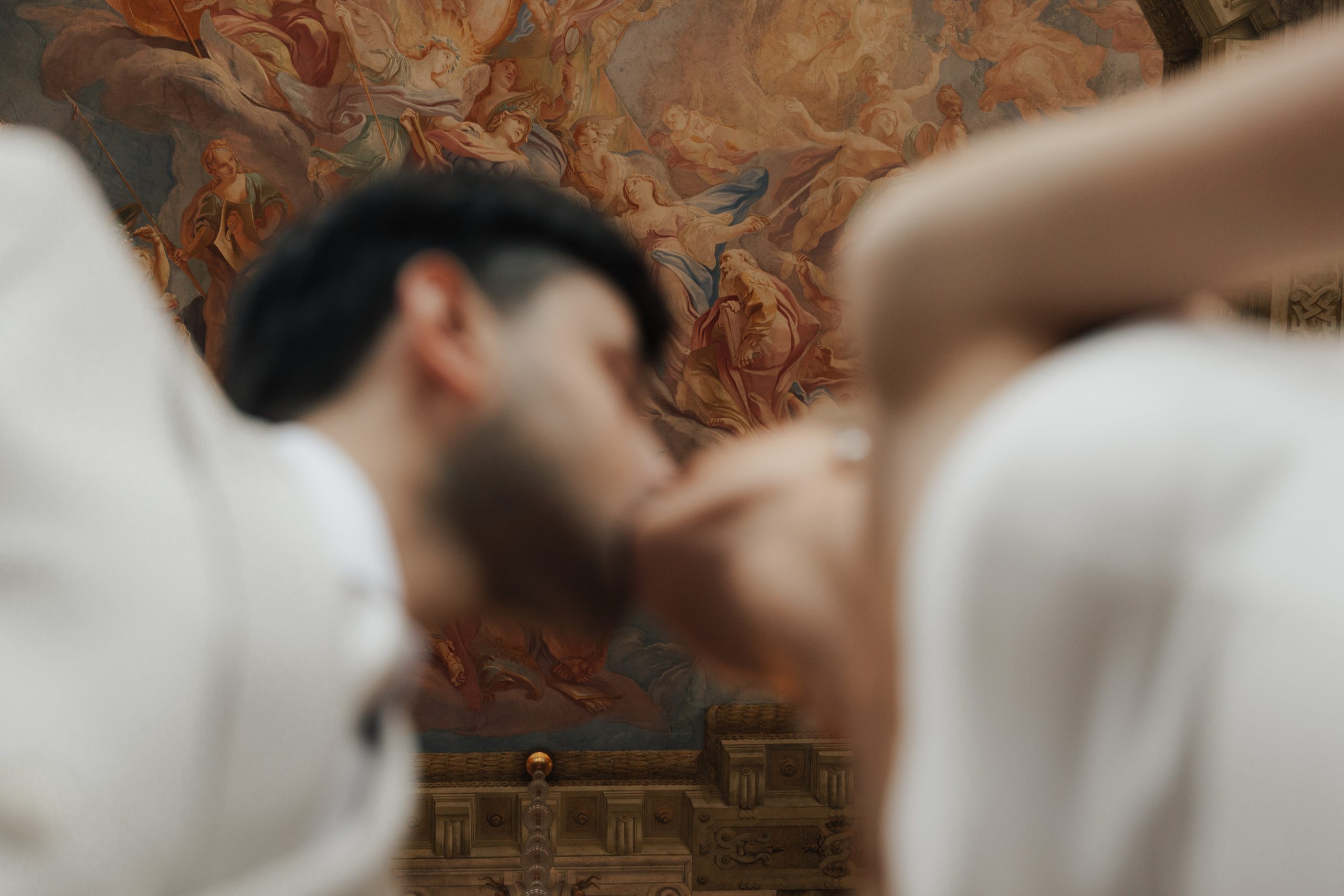 Bride and groom kissing beneath a baroque ceiling fresco in a Vienna palace, artistic editorial wedding photography