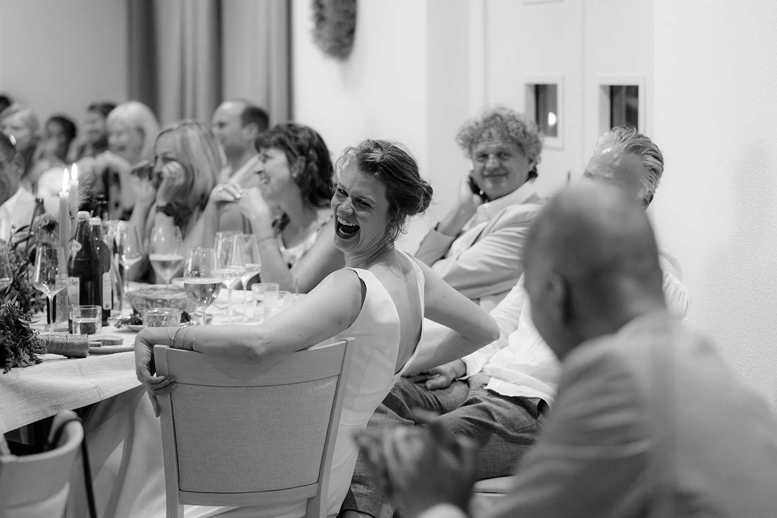 Black and white photo of guests laughing at the wedding dinner at Weingut K+K